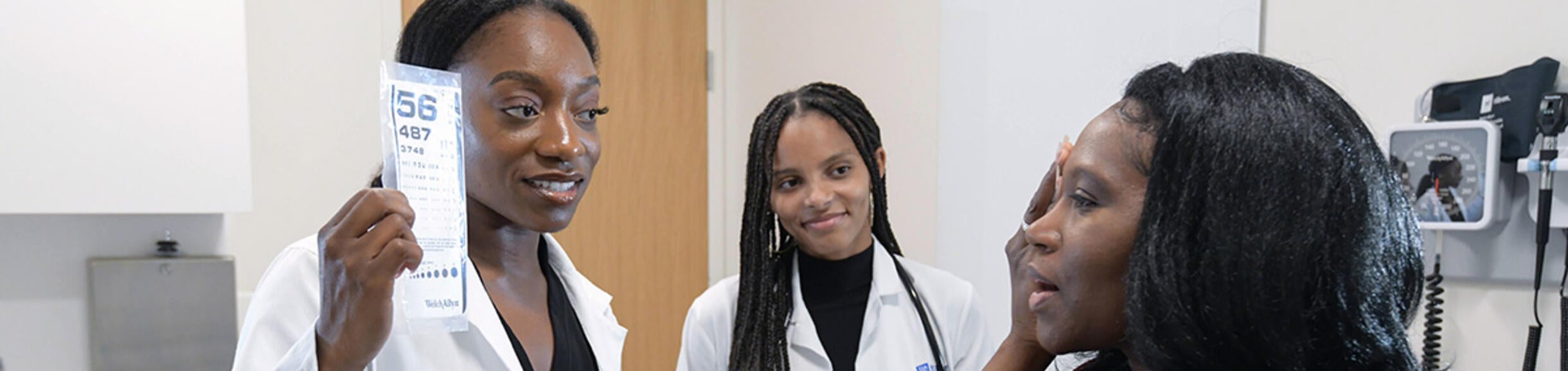 Two medical students performing an eye exam on a patient